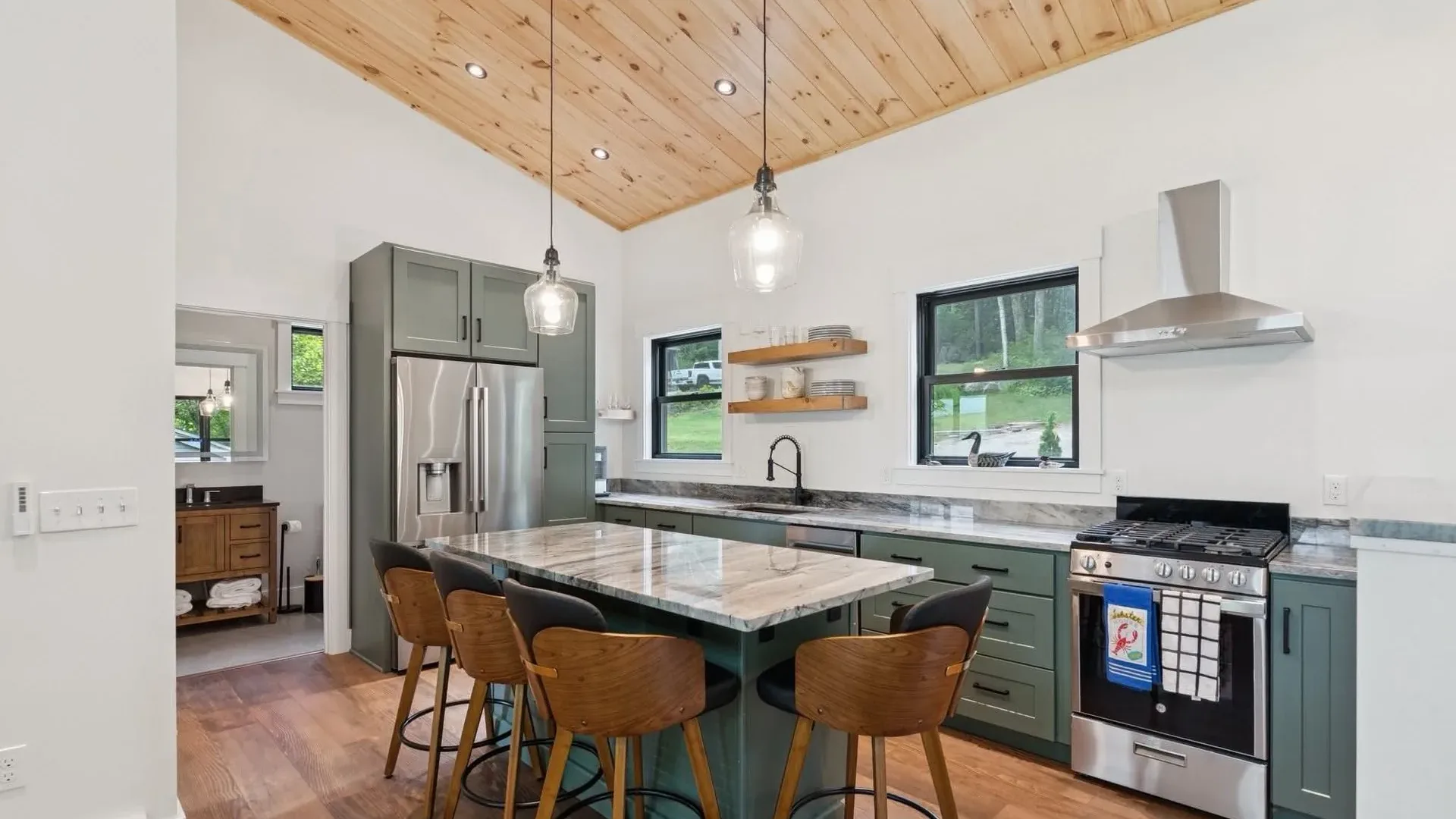 Kitchen with green cabinets, marble island, and wood ceiling